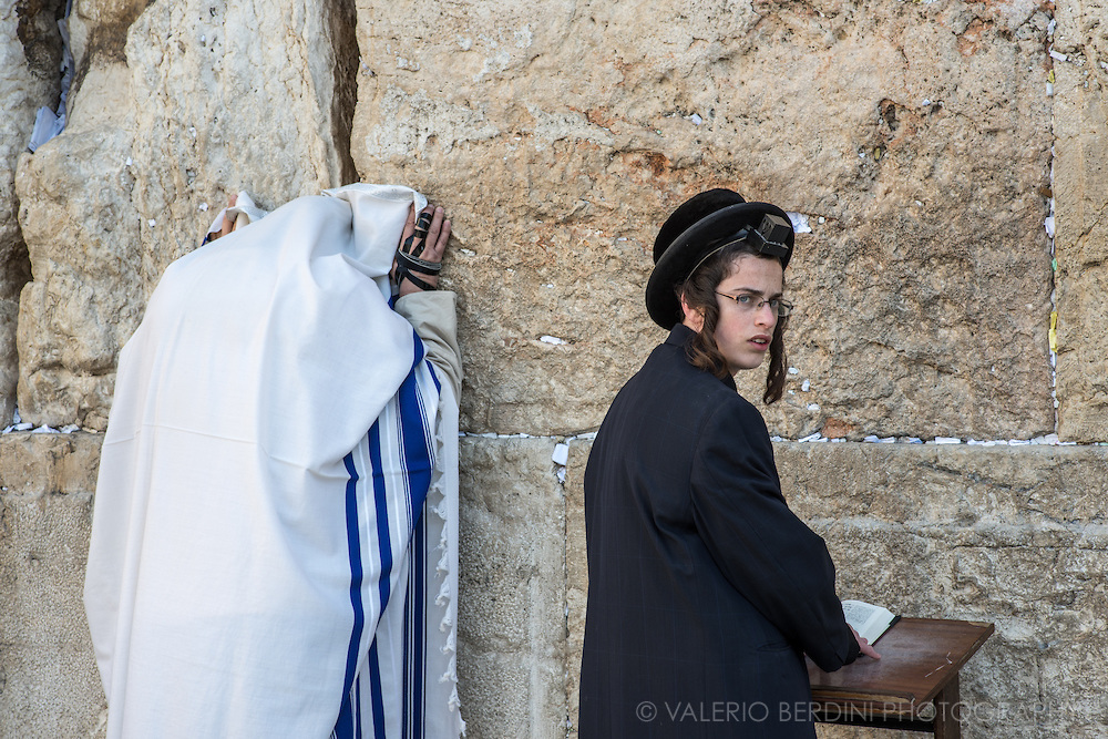 上图:哭墙晨祷。左边的男人披着祷告巾(Tallit Shawl),右手缠着经文匣(Arm Tefillin)。右边的男孩前额头上戴着经文匣(Head Tefillin)。经文匣里面藏着「示马」经文(申六4-9;十一13-21)。